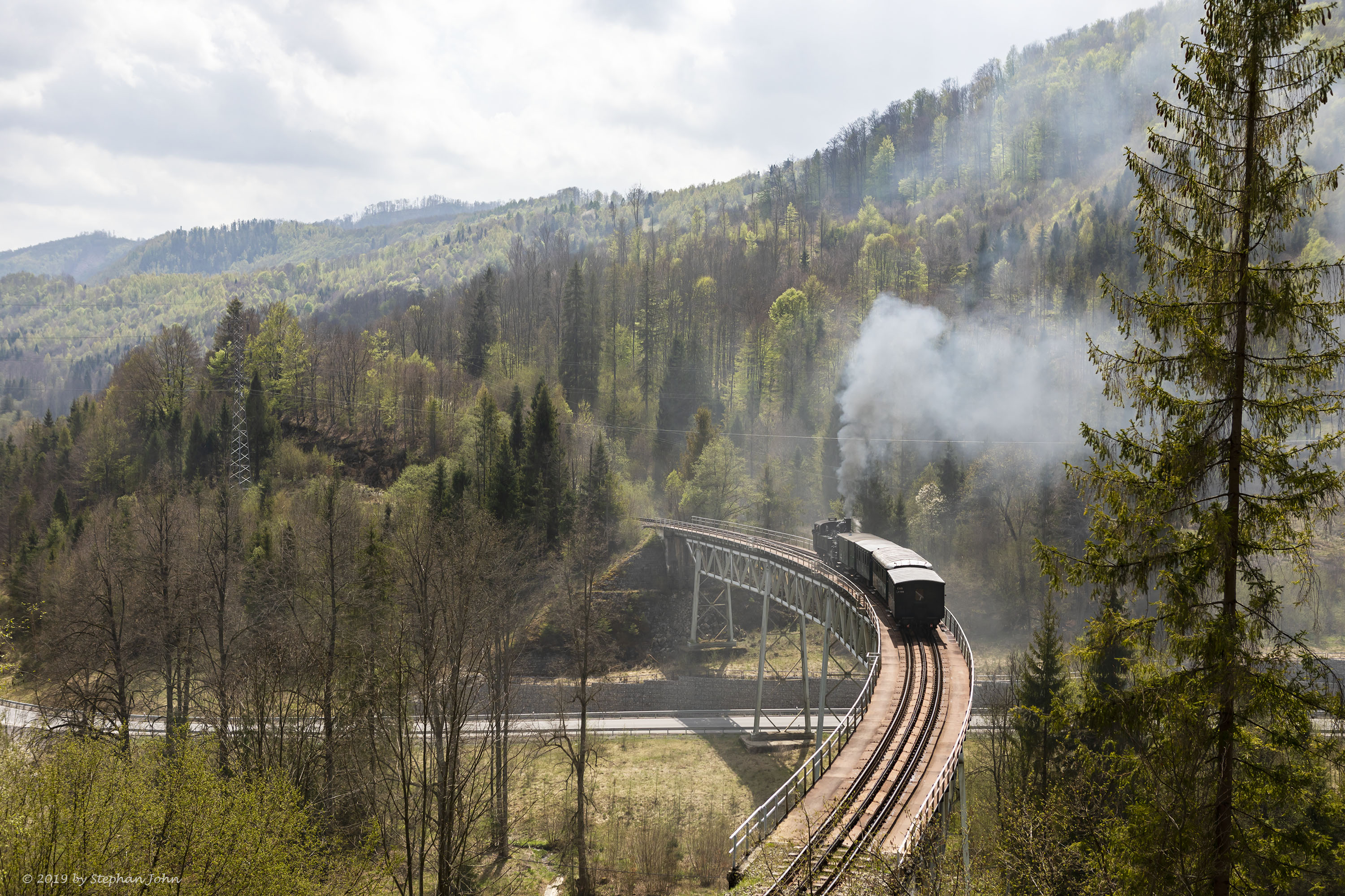 <p>Die Lok 4296 schiebt den Zug über die Steigung nach Zbojská. Hier befindet sich der Zug auf dem Viadukt 