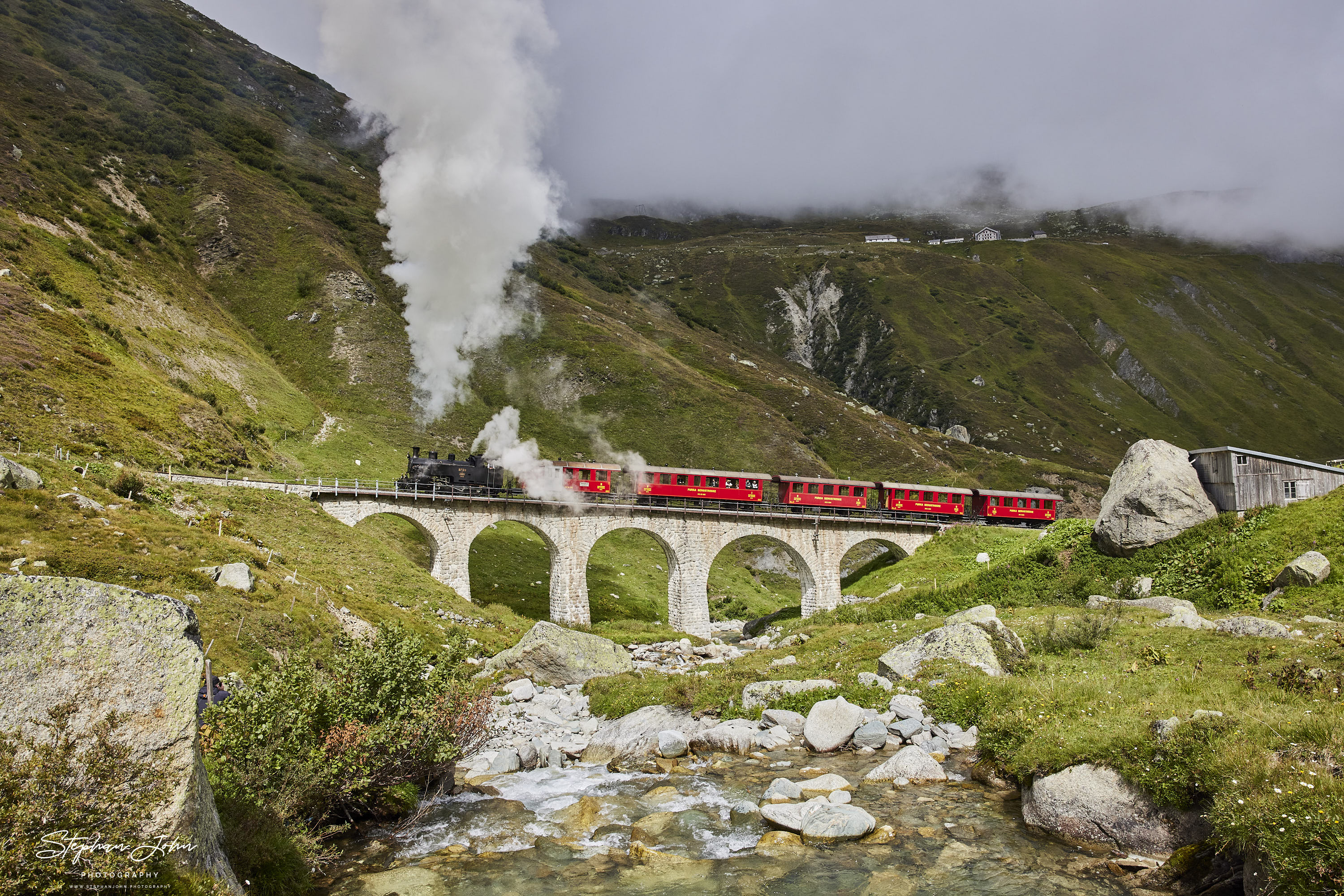 Lok 9 der DFB dampft mit einem Personenzug in Richtung Furka-Pass und Oberwald. Hier passiert der Zug das Steinstafelviadukt.