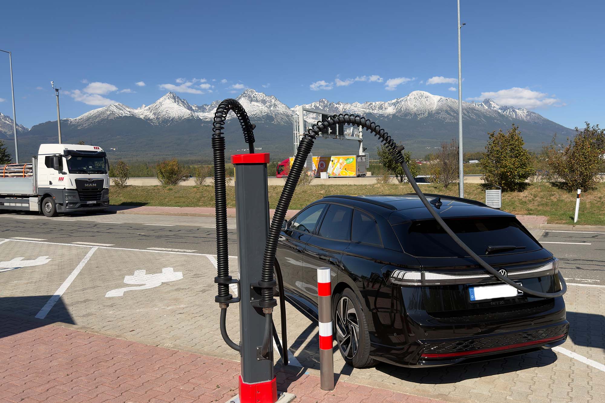 Auto an einer Ladesäule vor der Bergkulisse der Hohen Tatra