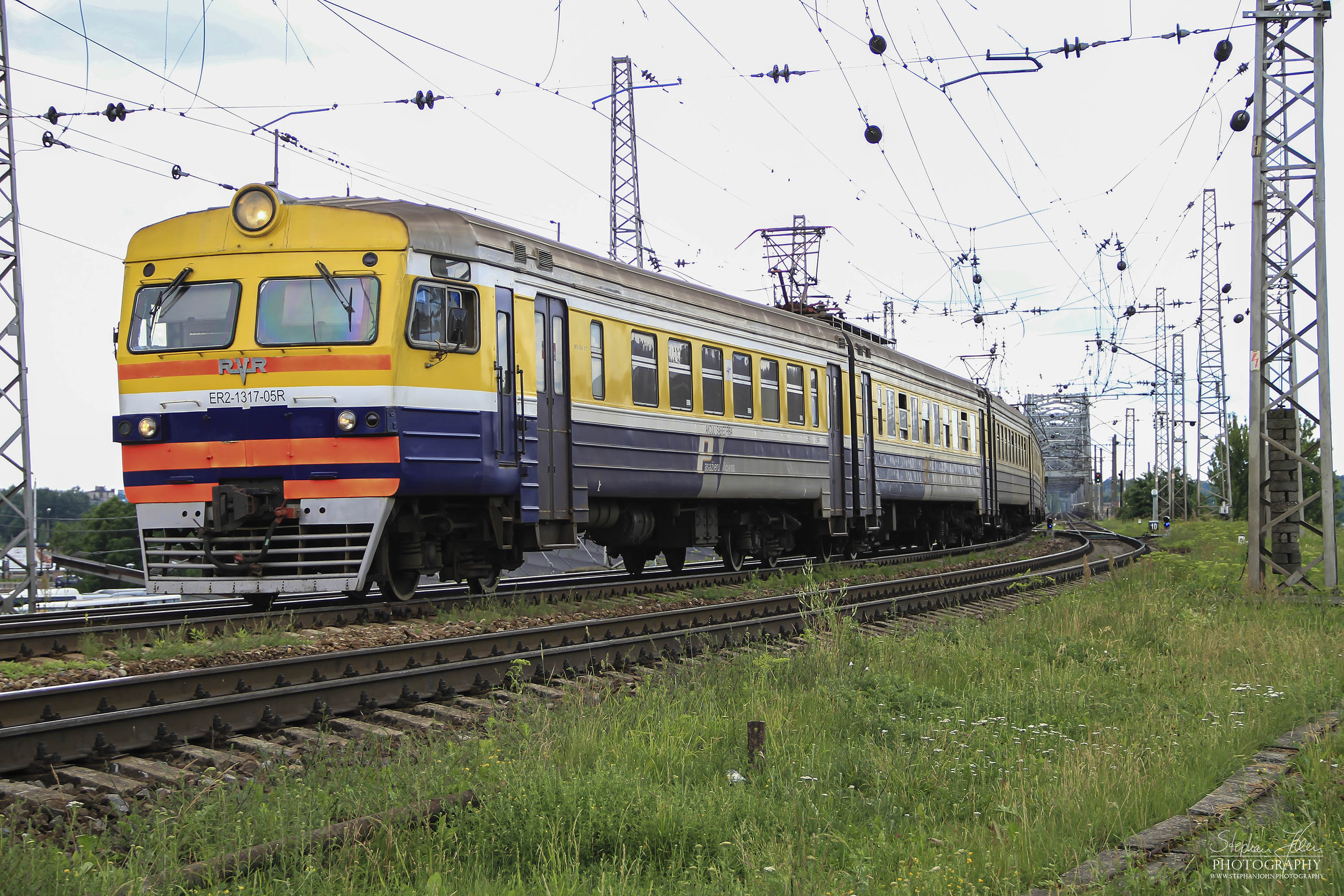 Triebwagenzug ER2-1317-05R hat die Brücke über die Düna passiert und erreicht den Bahnhof Riga