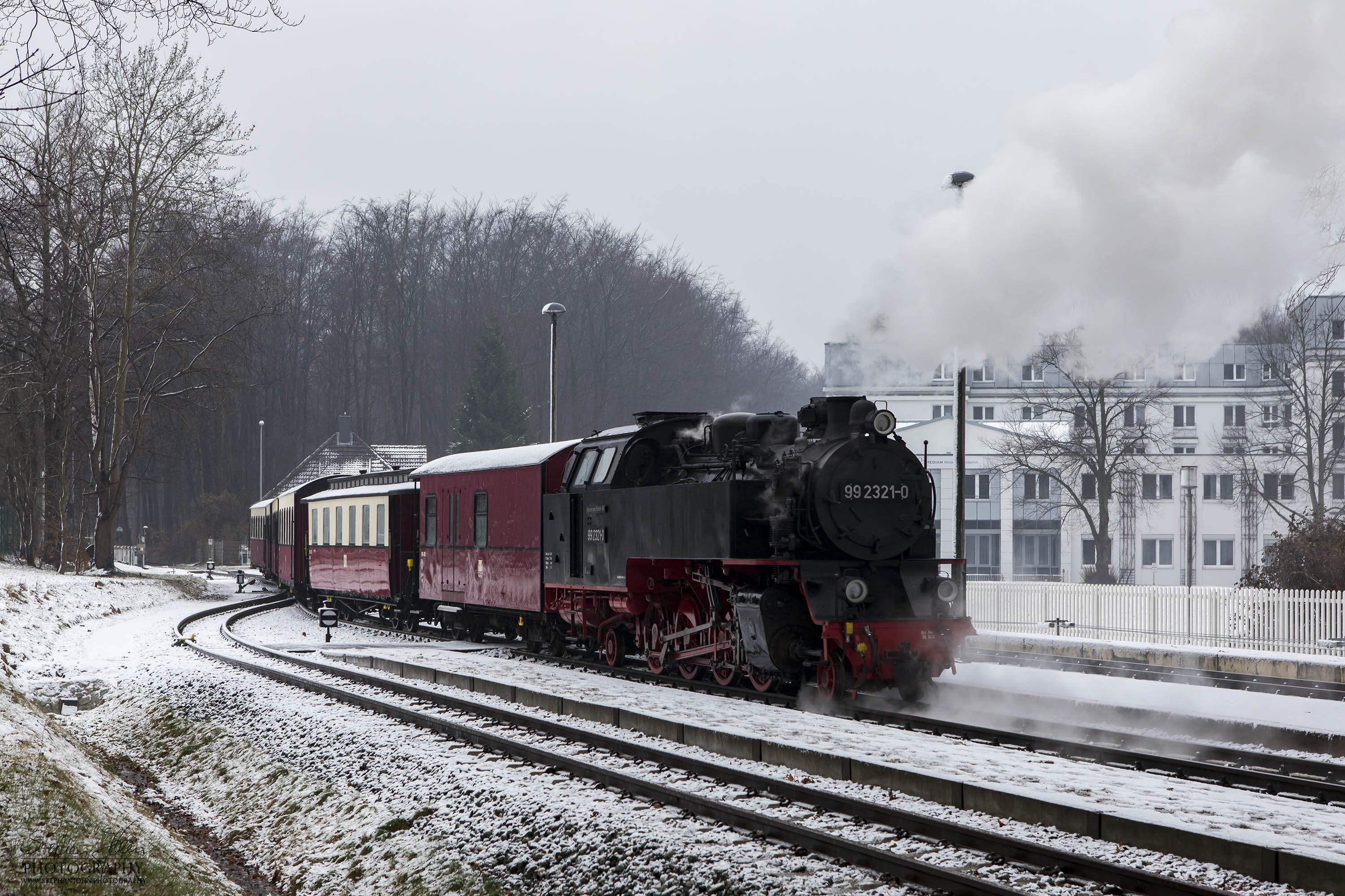 Lok 99 2321-0 mit einem Personenzug der Epoche IV während der Einfahrt in den Bahnhof Heiligendamm. Die Zugbildung entspricht der Zeit zwischen 1980 und 1983, als die Personenwagen modernisiert wurden.