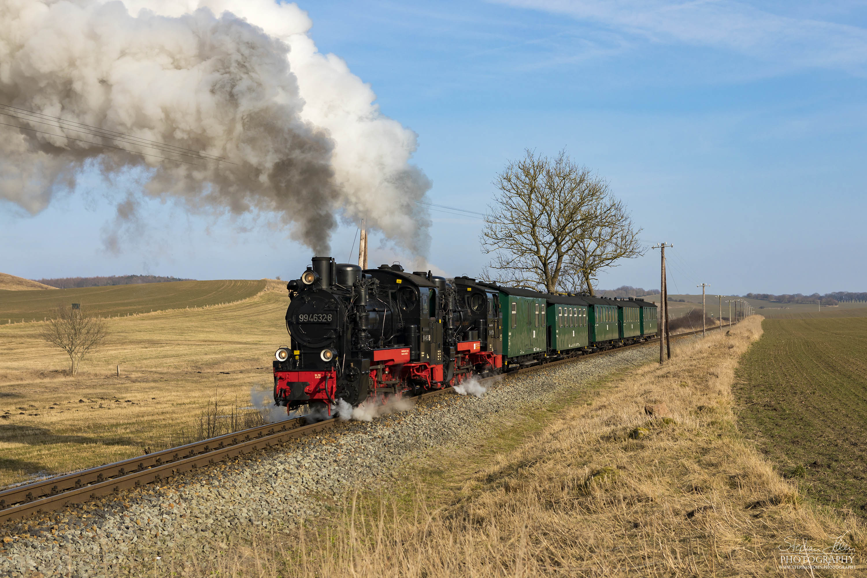 Seit der Hauptuntersuchung im Januar 2018 hat die Rügen-Lok 99 4632-8 (Vulcan-Lok) wieder eine schwarze Reichsbahnlackierung. Die Rügen-Lok 99 4633-6 hat noch in diesem Jahr Fristablauf und kommt dann in grüner Farbgebung wieder. Beide Rügenloks in schwarzer Farbgebung ist also nur ein kurzes Vergnügen. Hier zieht die Lok 99 4633-6 mit Vorspannlok 99 4632-8 zwischen Seelvitz und Posewald einen Personenzug in Richtung Putbus. 
