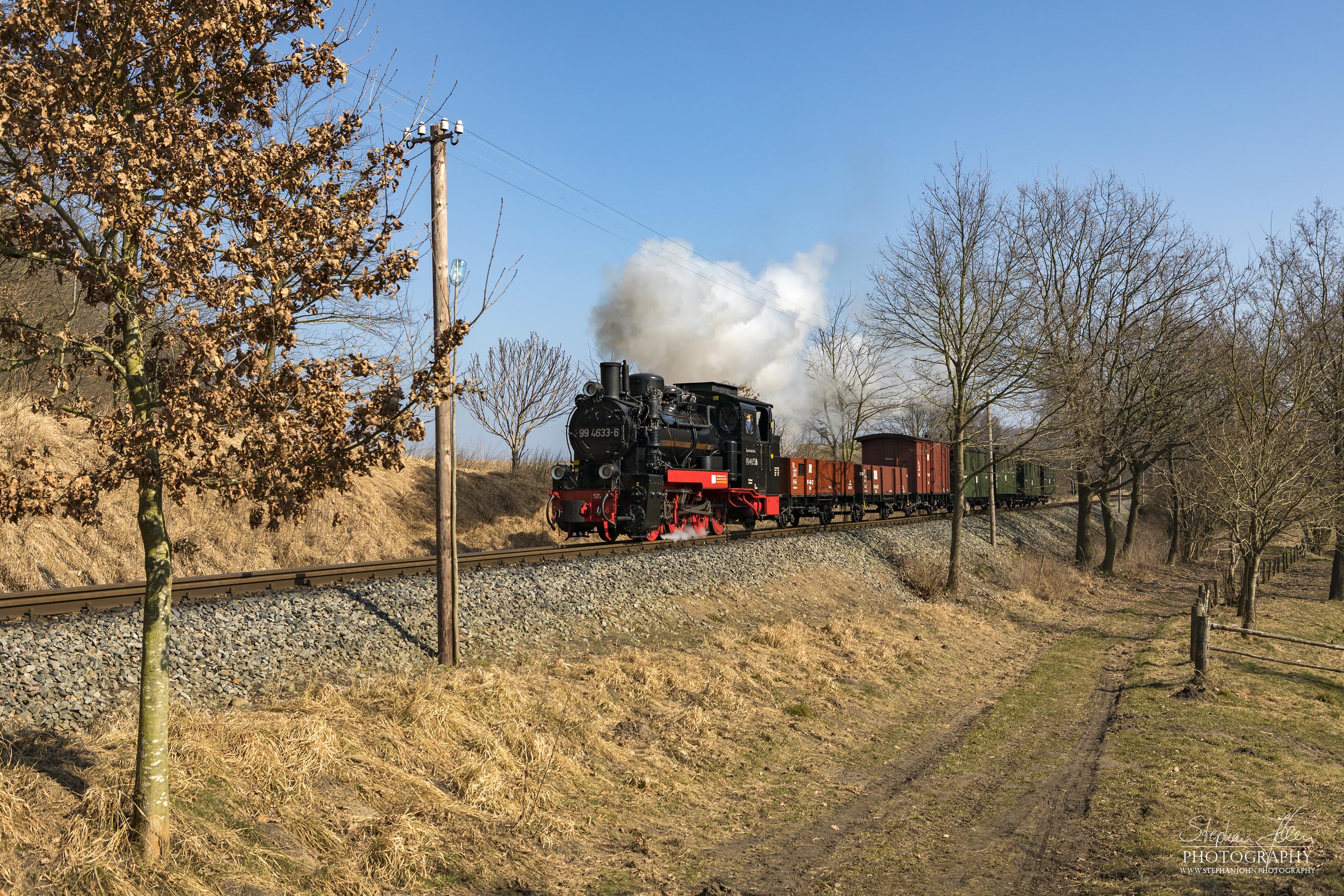 Die Rügen-Lok 99 4633-6 dampft mit einem GmP in Richtung Putbus. Gleich kommt der Zug  zum Bahnübergang in Nistelitz