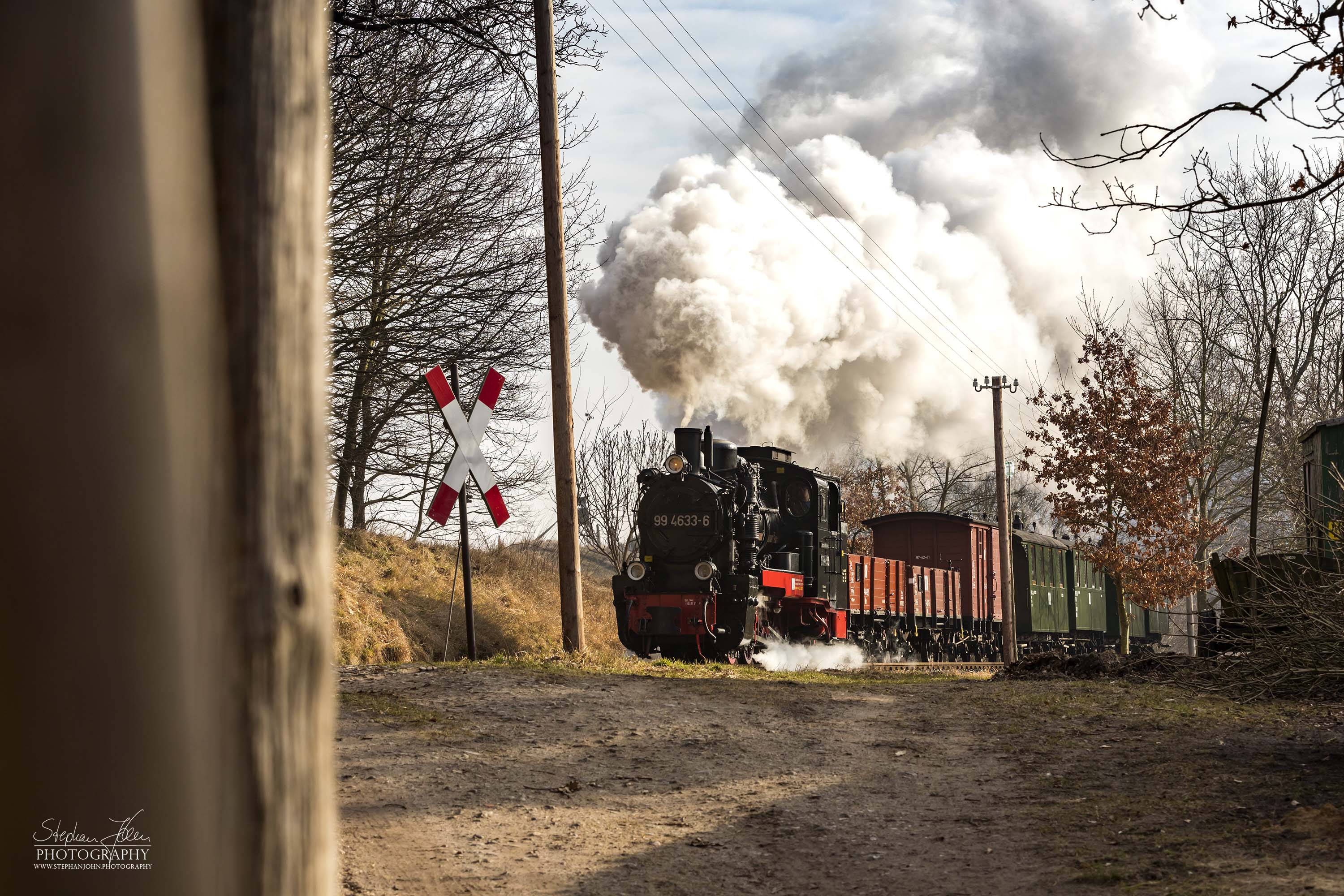 Die Rügen-Lok 99 4633-6 dampft mit einem GmP in Richtung Putbus. Hier wird gerade der unbeschrankte Bahnübergang in Nistelitz passiert