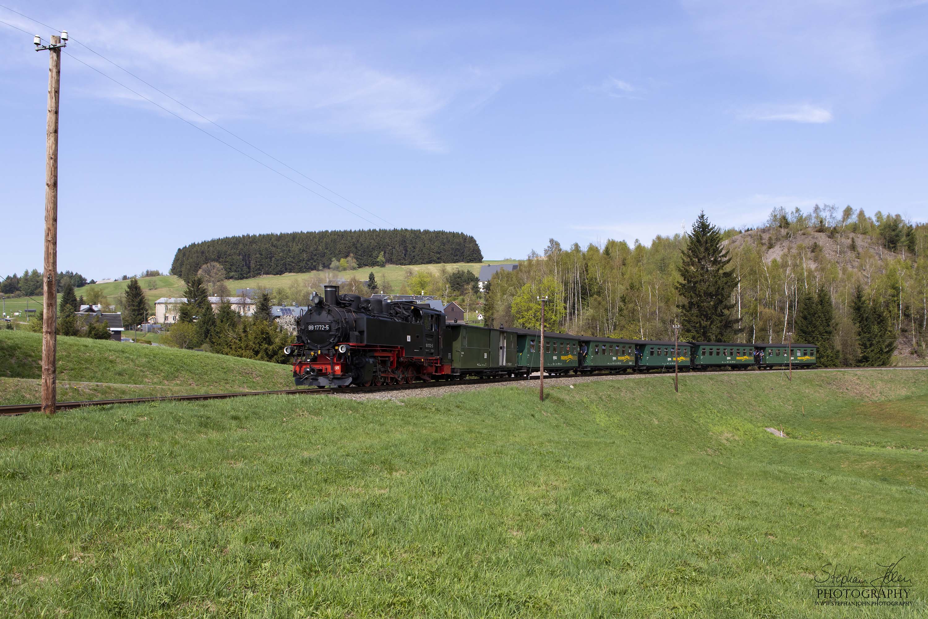 Zug P 1003 mit Lok 99 1772-5 auf dem Weg von Cranzahl nach Oberwiesenthal. Nachdem der Zug den Bahnhof Niederschlag verlassen hat, dampft er weiter in Richtung Hammerunterwiesenthal. 