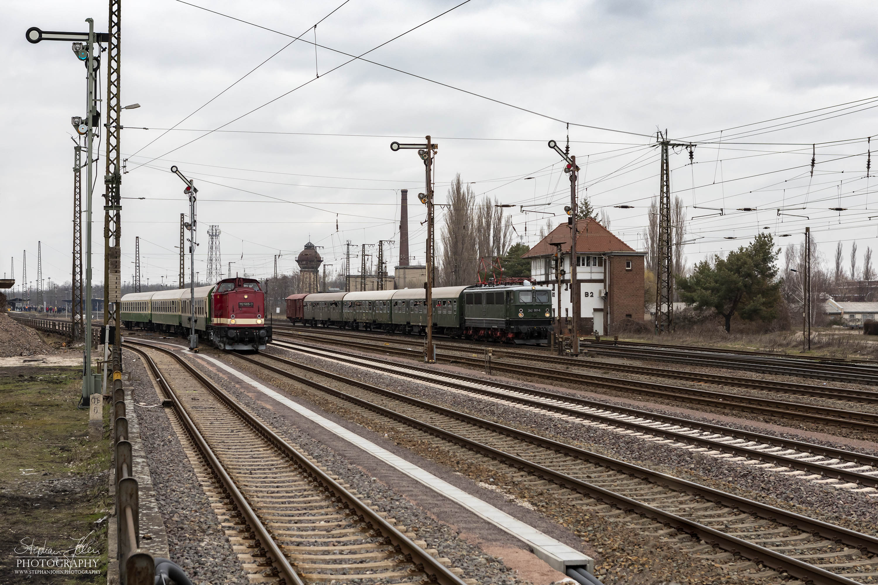 Zug 74324 mit Lok 112 565-7 von Dessau Hbf nach Bernburg und Zug 61424 mit Lok 242 001-6 von Calbe Ost nach Niemberg verlassen den Bahnhof Köthen.