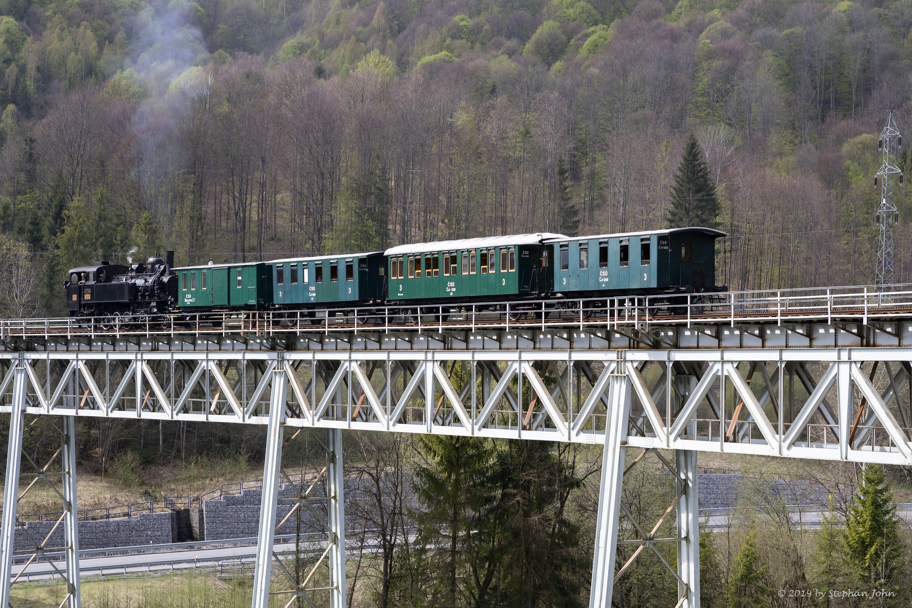 <p>Die Lok 4296 schiebt den Zug über die Steigung nach Zbojská. Hier befindet sich der Zug auf dem Viadukt 