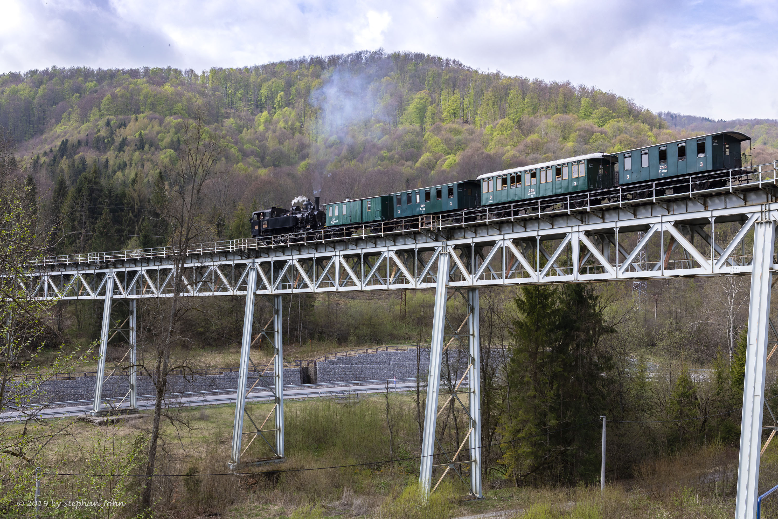 <p>Die Lok 4296 schiebt den Zug über die Steigung nach Zbojská. Hier befindet sich der Zug auf dem Viadukt 