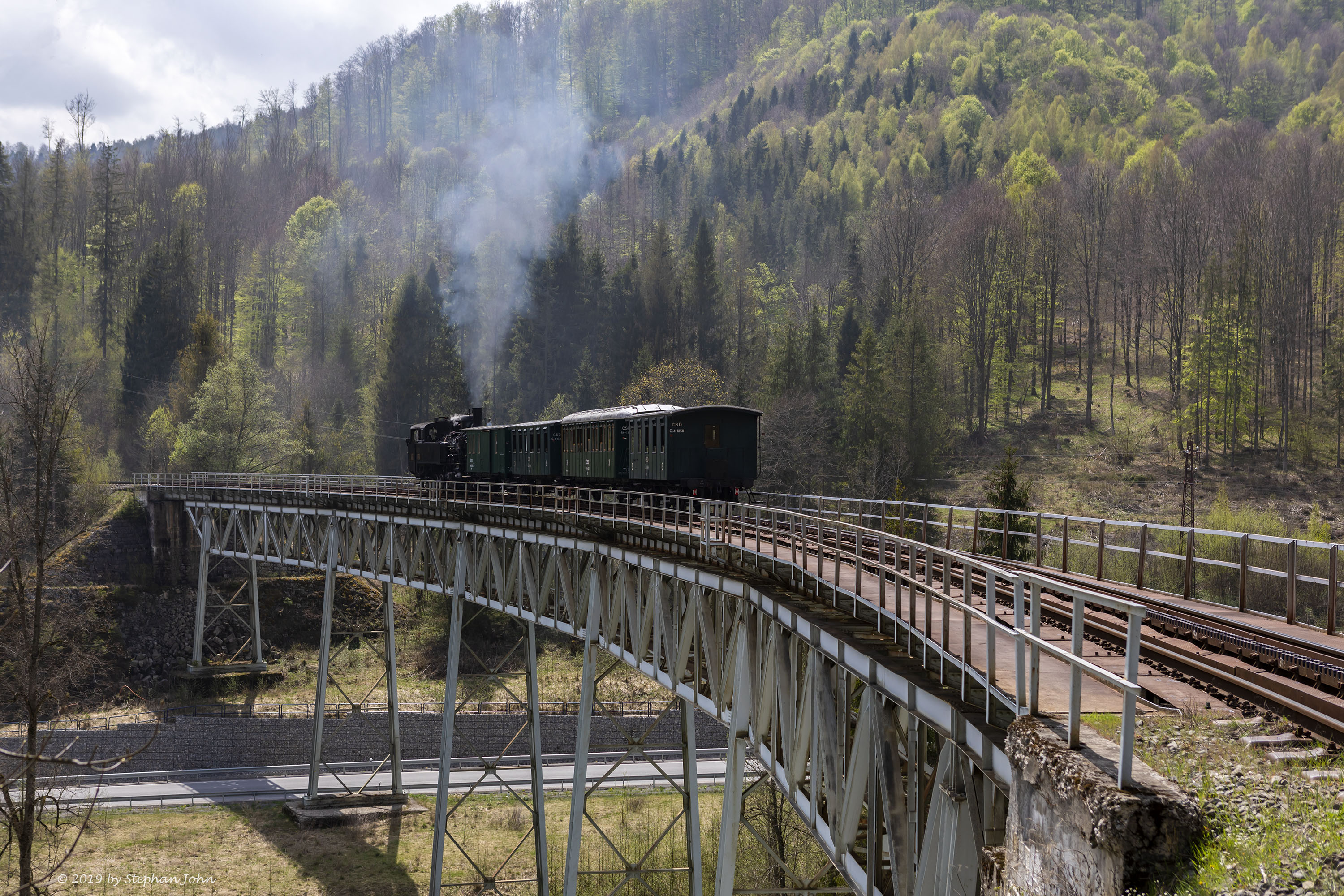 <p>Die Lok 4296 schiebt den Zug über die Steigung nach Zbojská. Hier befindet sich der Zug auf dem Viadukt 