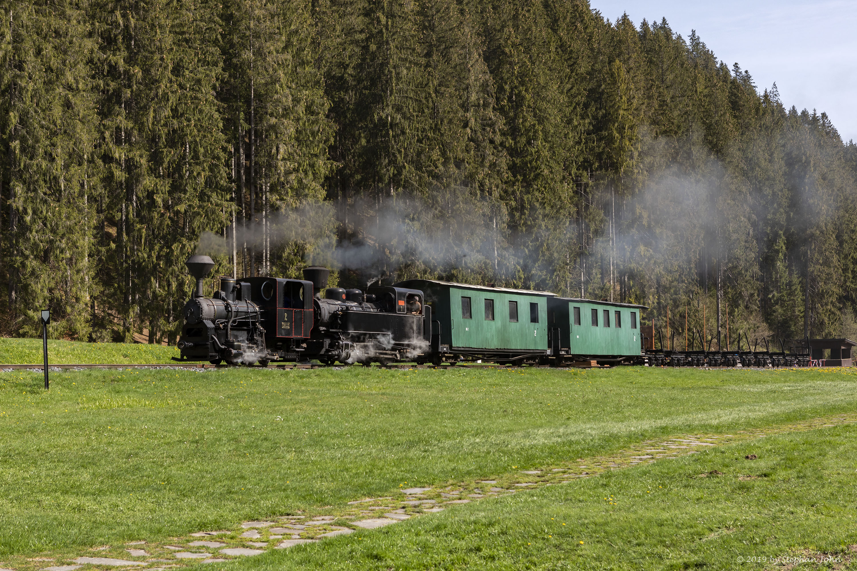Ein Zug der Waldbahn dampft mit zwei Lokomotiven die Strecke in Richtung Vydrovo entlang