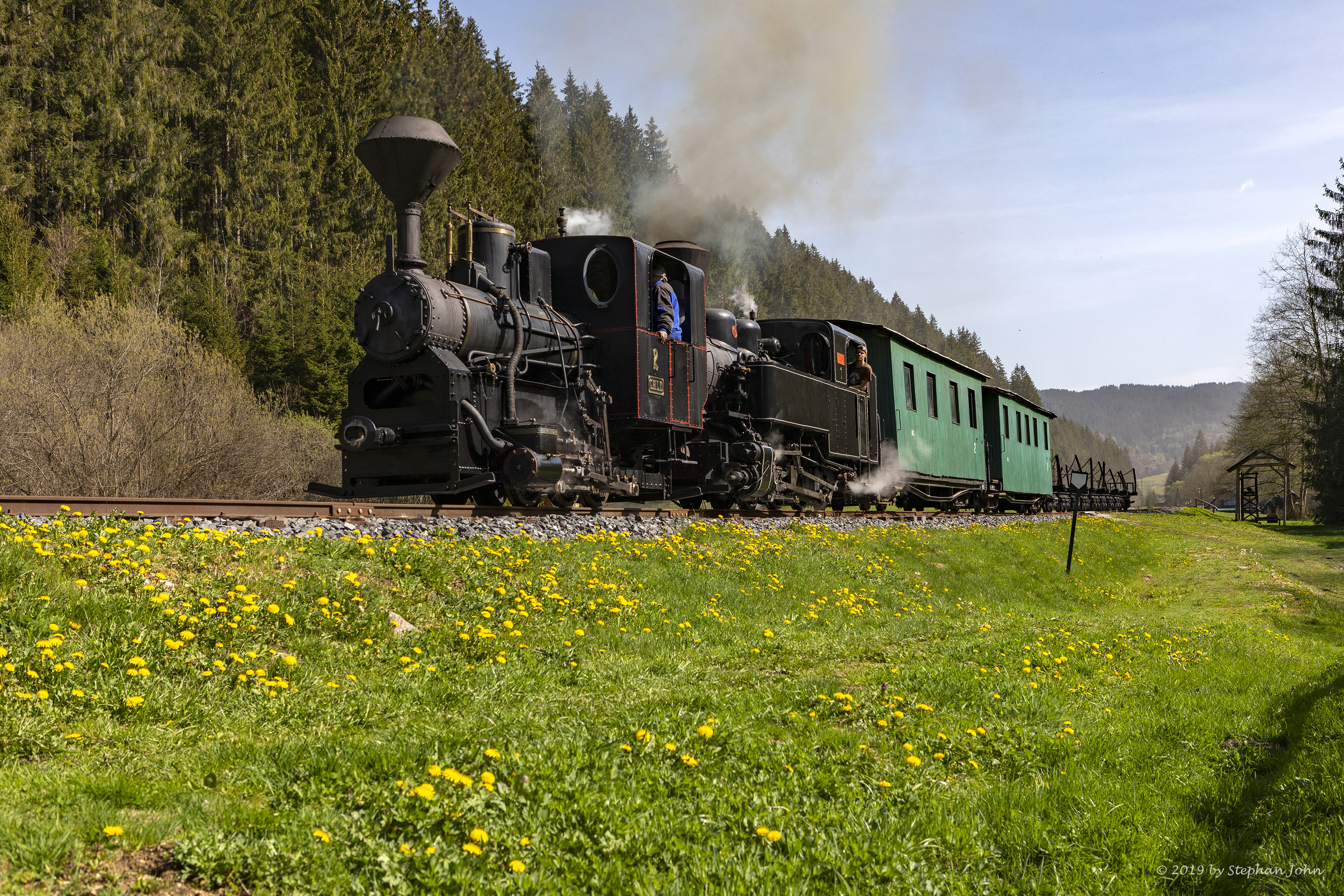 <p>Ein Zug der Waldbahn dampft mit zwei Lokomotiven die Strecke in Richtung Vydrovo entlang</p>