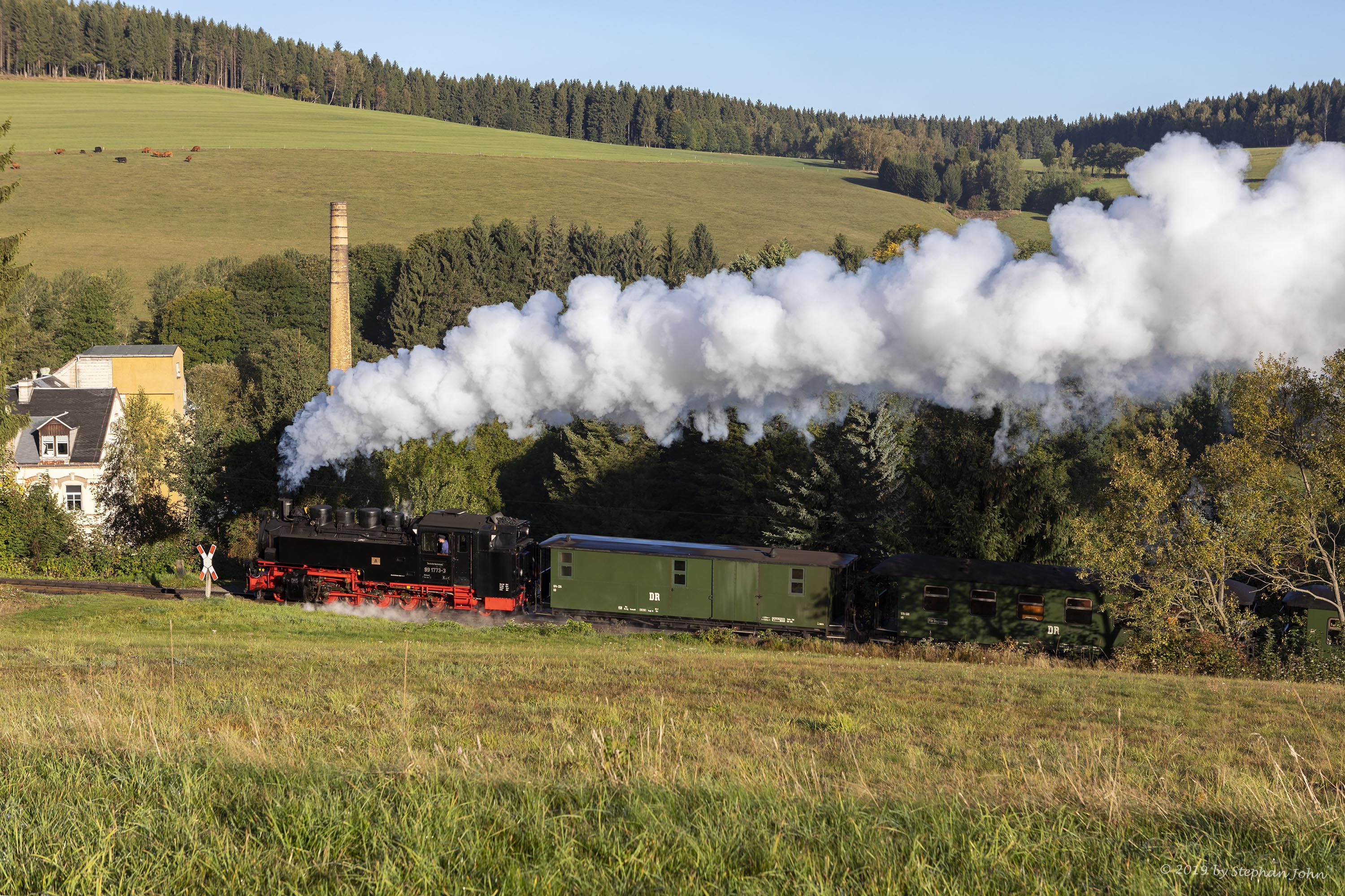 Zug 9005 mit Lok 99 1773-3 fährt mit dem Personenzug in Richtung Oberwiesenthal und passiert hier einen Bahnübergang in Neudorf.