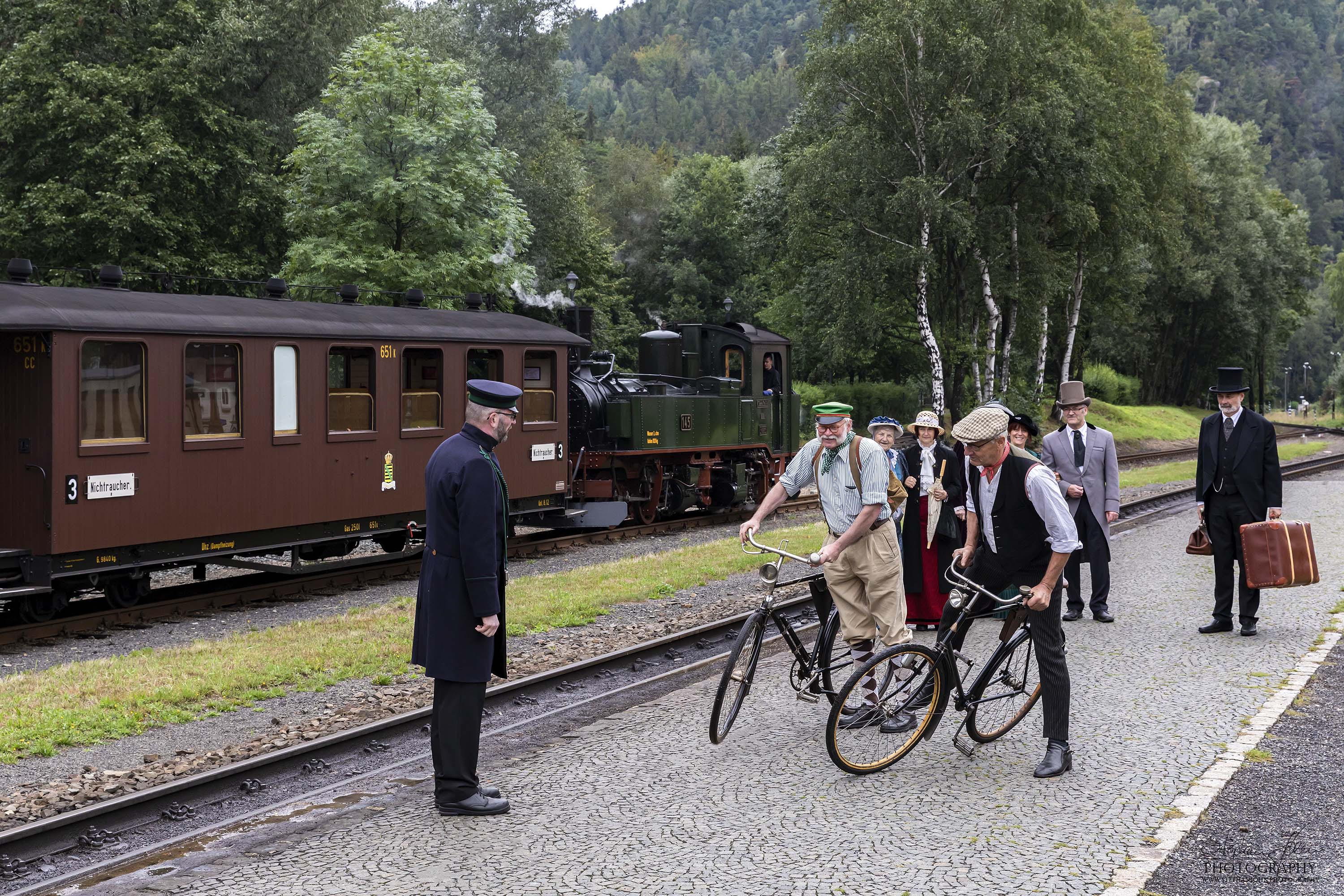 Auch damals schon war das Radfahren auf dem Bahnsteig nicht gestattet. Nachdem der Bahnbeamte die zwei Radfahrer darauf hingewiesen hat, werden die Räder über den Bahnsteig geschoben.