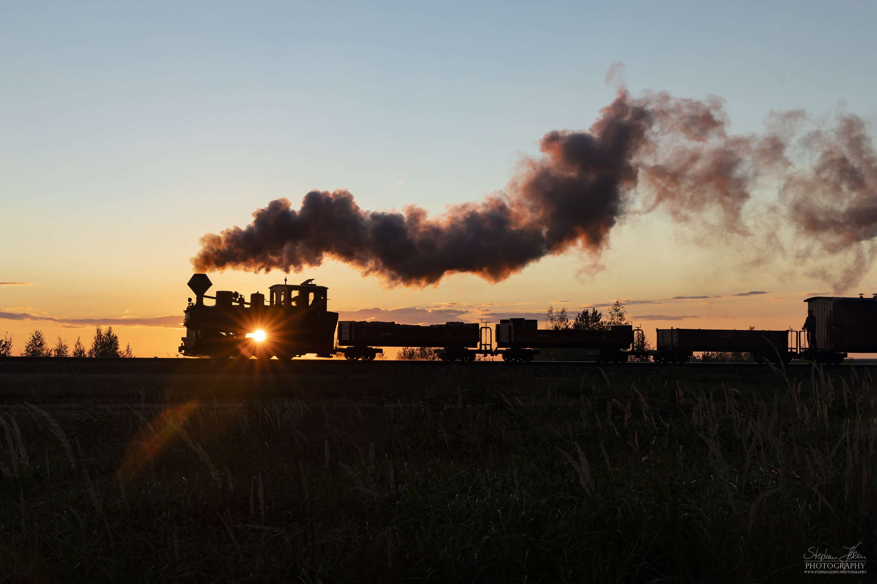 Lok 99 3312 zieht einen Güterzug im Sonnenuntergang zum Schweren Berg