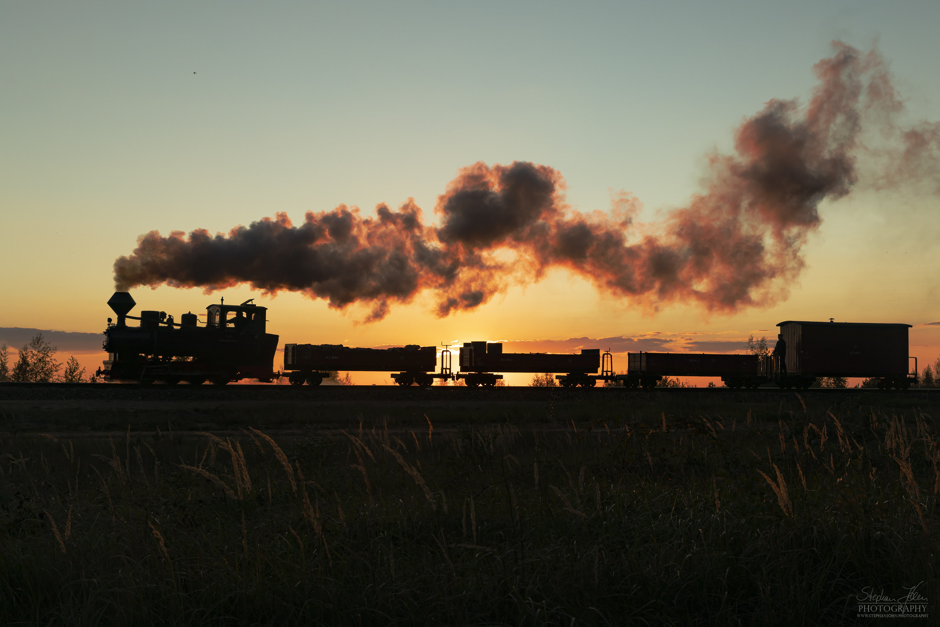 Lok 99 3312 zieht einen Güterzug im Sonnenuntergang zum Schweren Berg