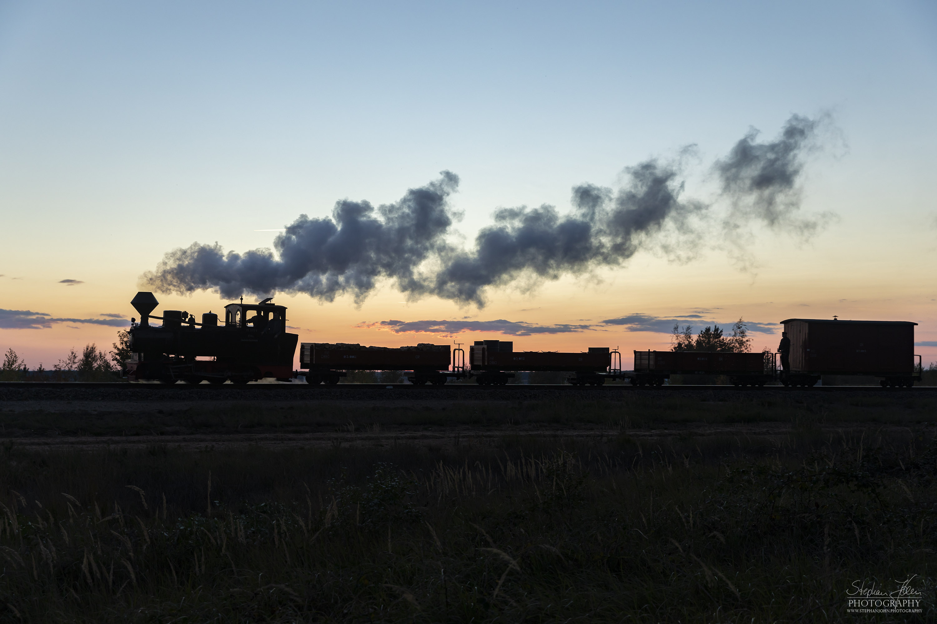 Lok 99 3312 zieht einen Güterzug im Sonnenuntergang zum Schweren Berg