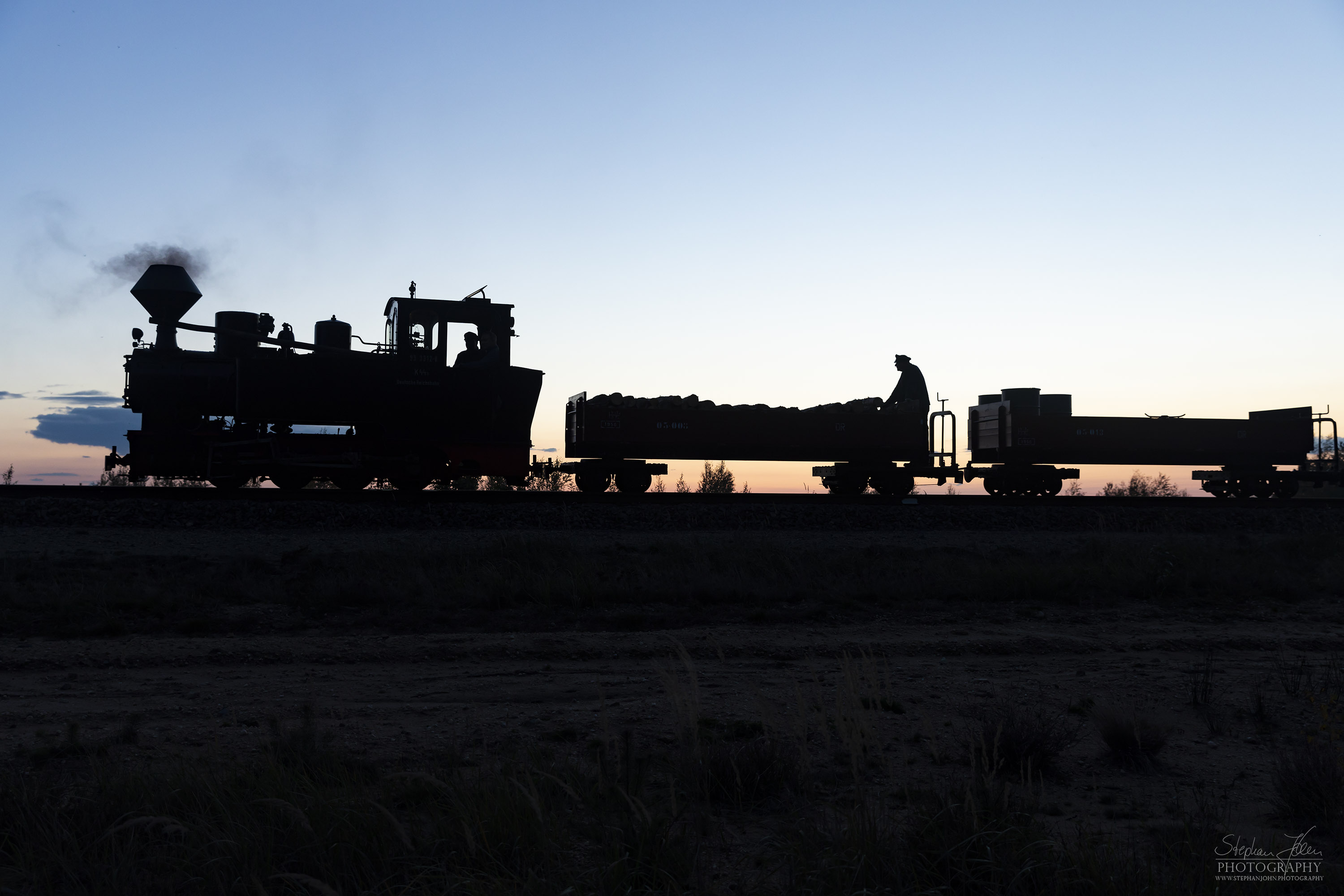 Lok 99 3312 zieht einen Güterzug im Sonnenuntergang zum Schweren Berg