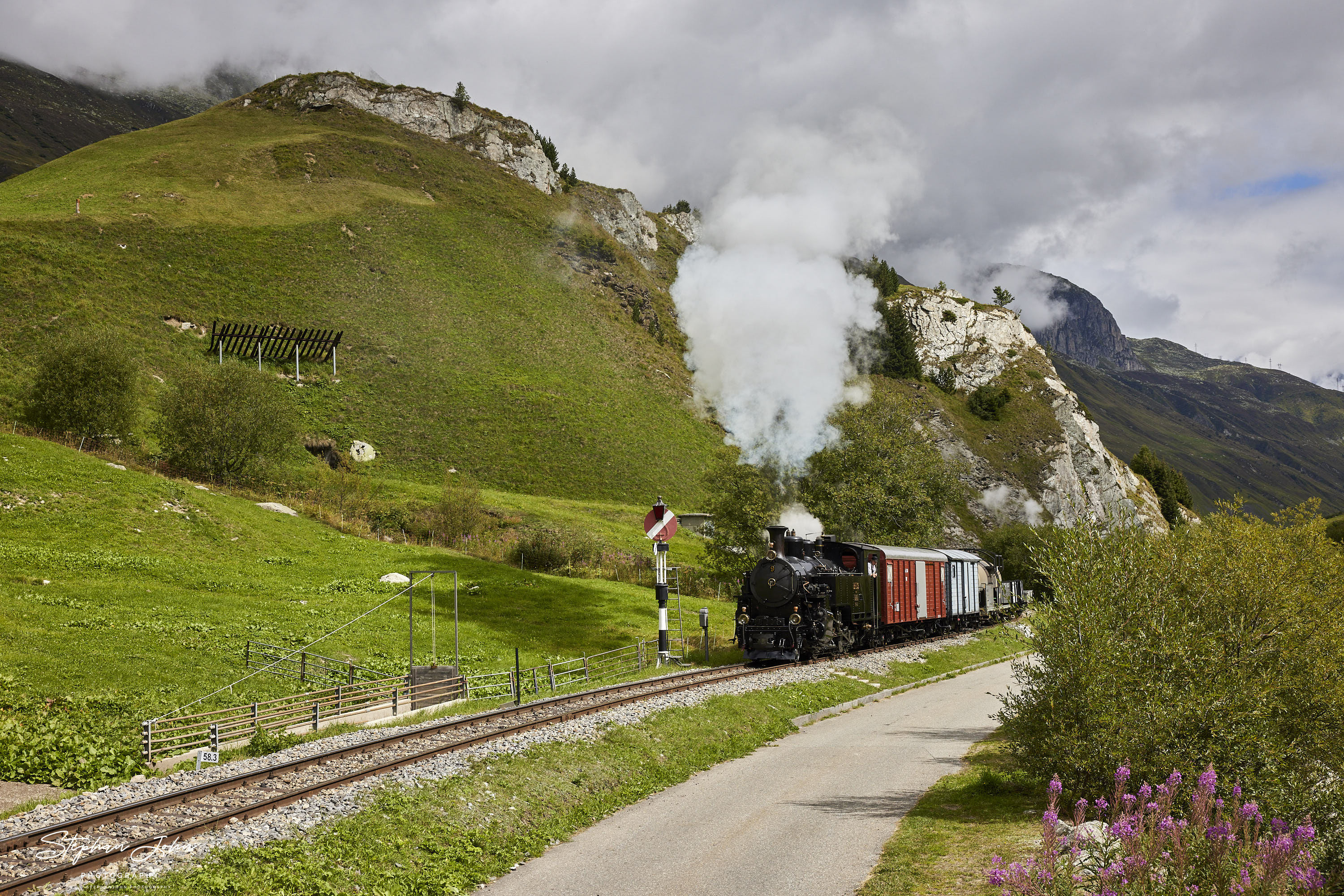 Lok 9 der DFB verlässt mit einem Güterzug die Ortslage Realp und dampft in Richtung Furka-Pass. Hier passiert der Zug das Einfahrtsignal von Realp.