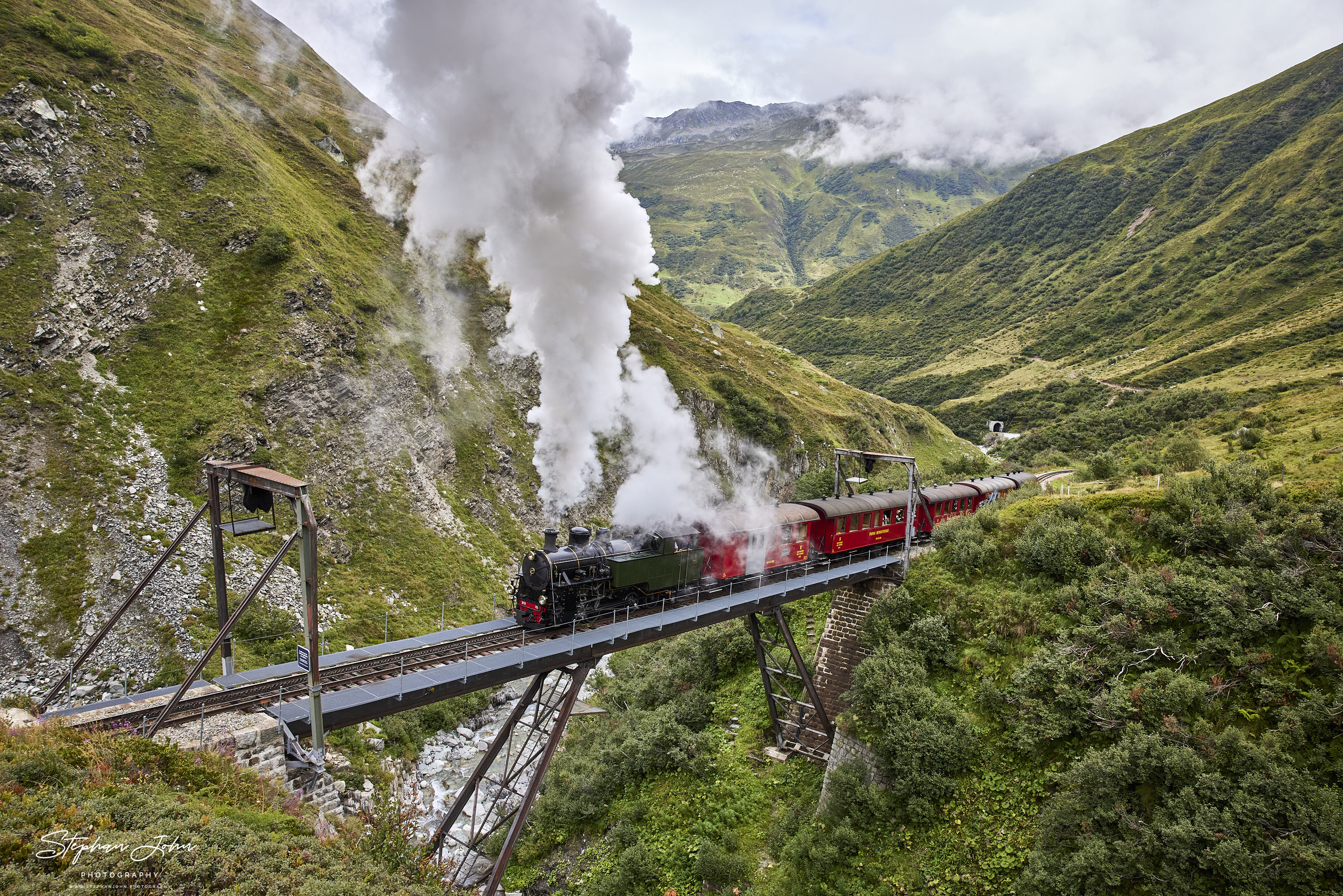 Lok 704 der DFB dampft mit einem Personenzug von Realp in Richtung Furka-Pass - Oberwald und passiert die Steffenbachbrücke. https://www.dfb.ch/de/stories/steffenbachbruecke