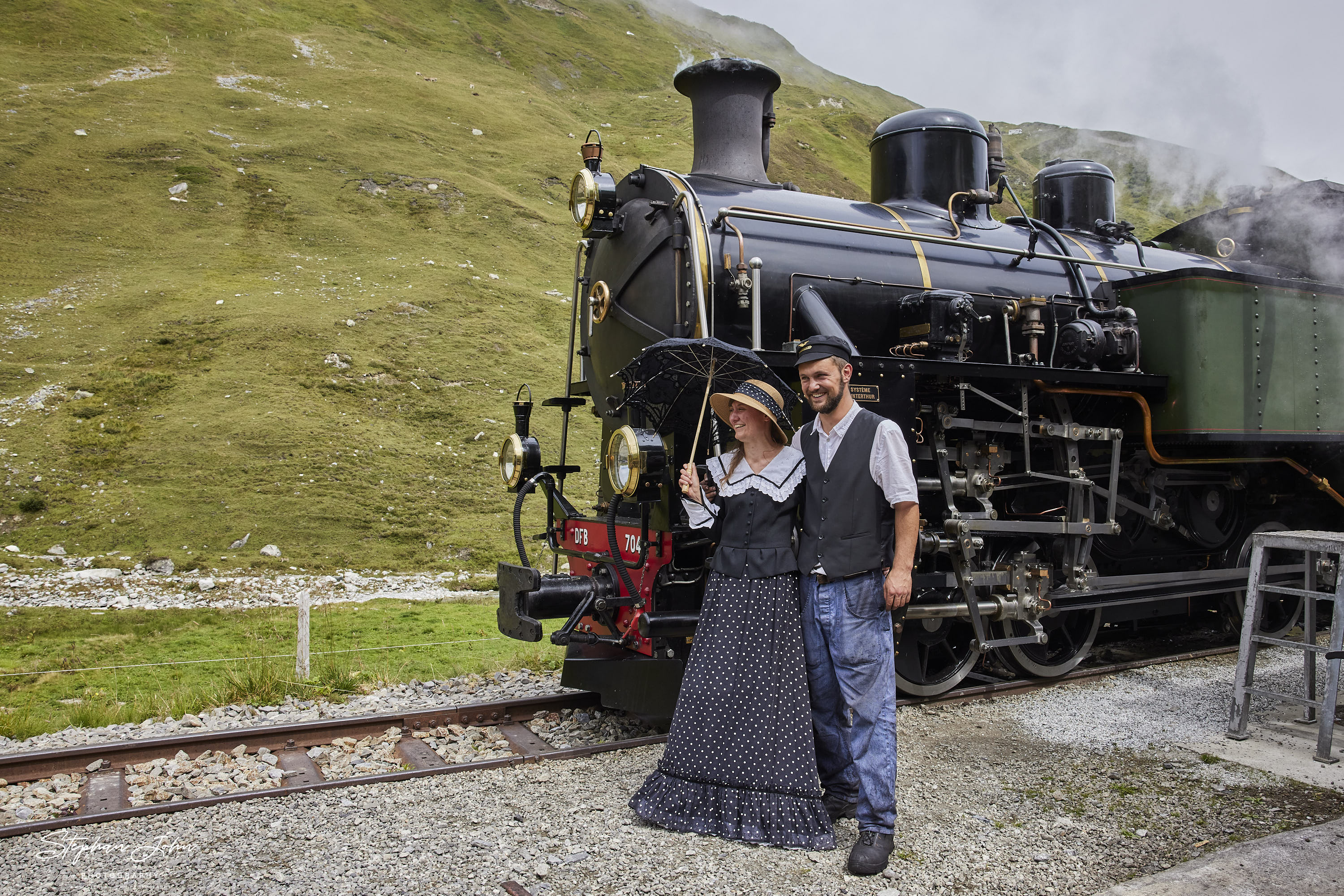 Im Bahnhof Tiefenbach müssen die Lokomotiven vom Personenzug und vom Güterzug Wasser nehmen um die Steigung zum Furka-Pass bewältigen zu können. Die Reisenden nutzen den Aufenthalt für einen Plausch.