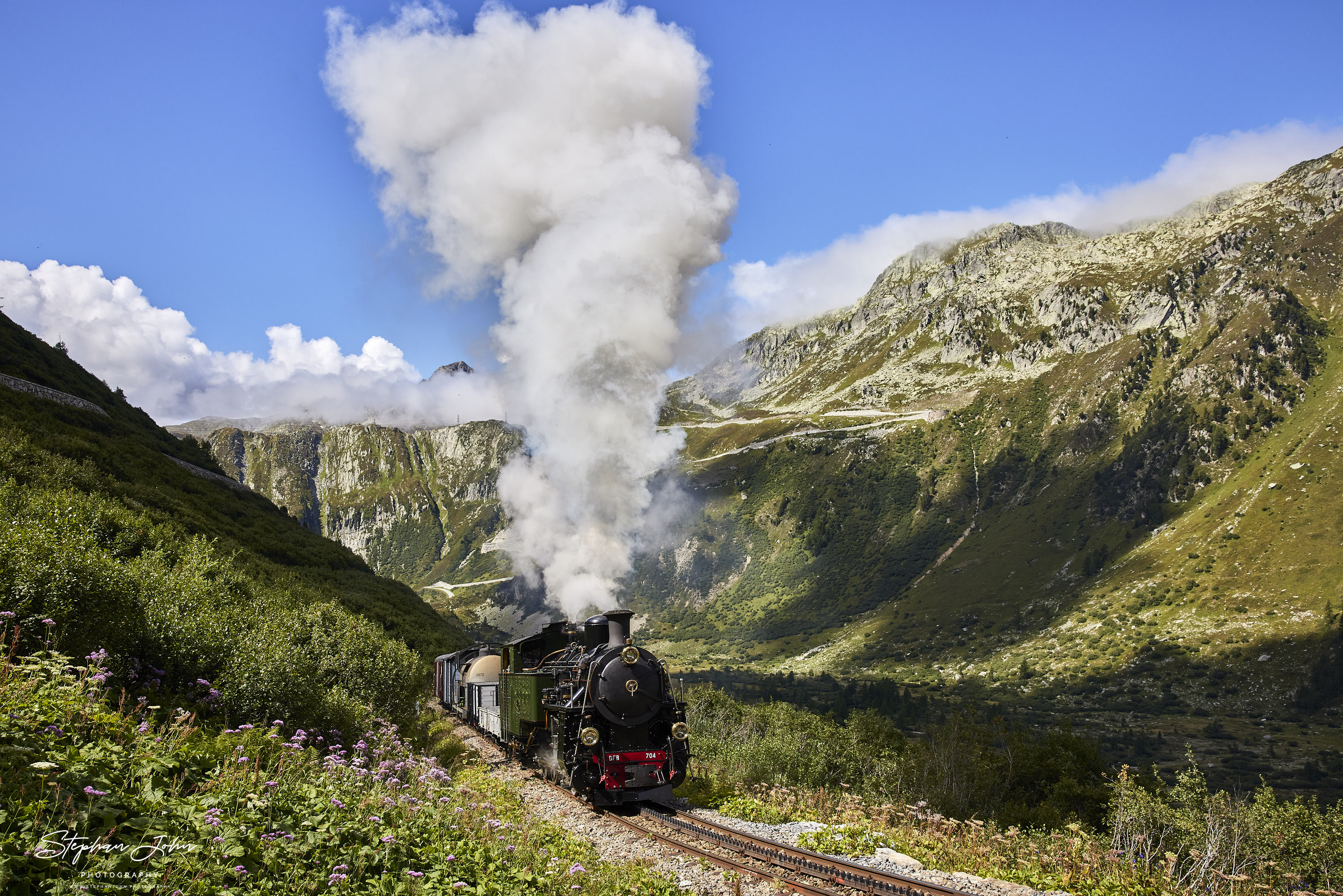 Lok 704 der DFB dampft mit einem Güterzug die Steigung von Gletsch nach Muttbach-Belvedere hoch.