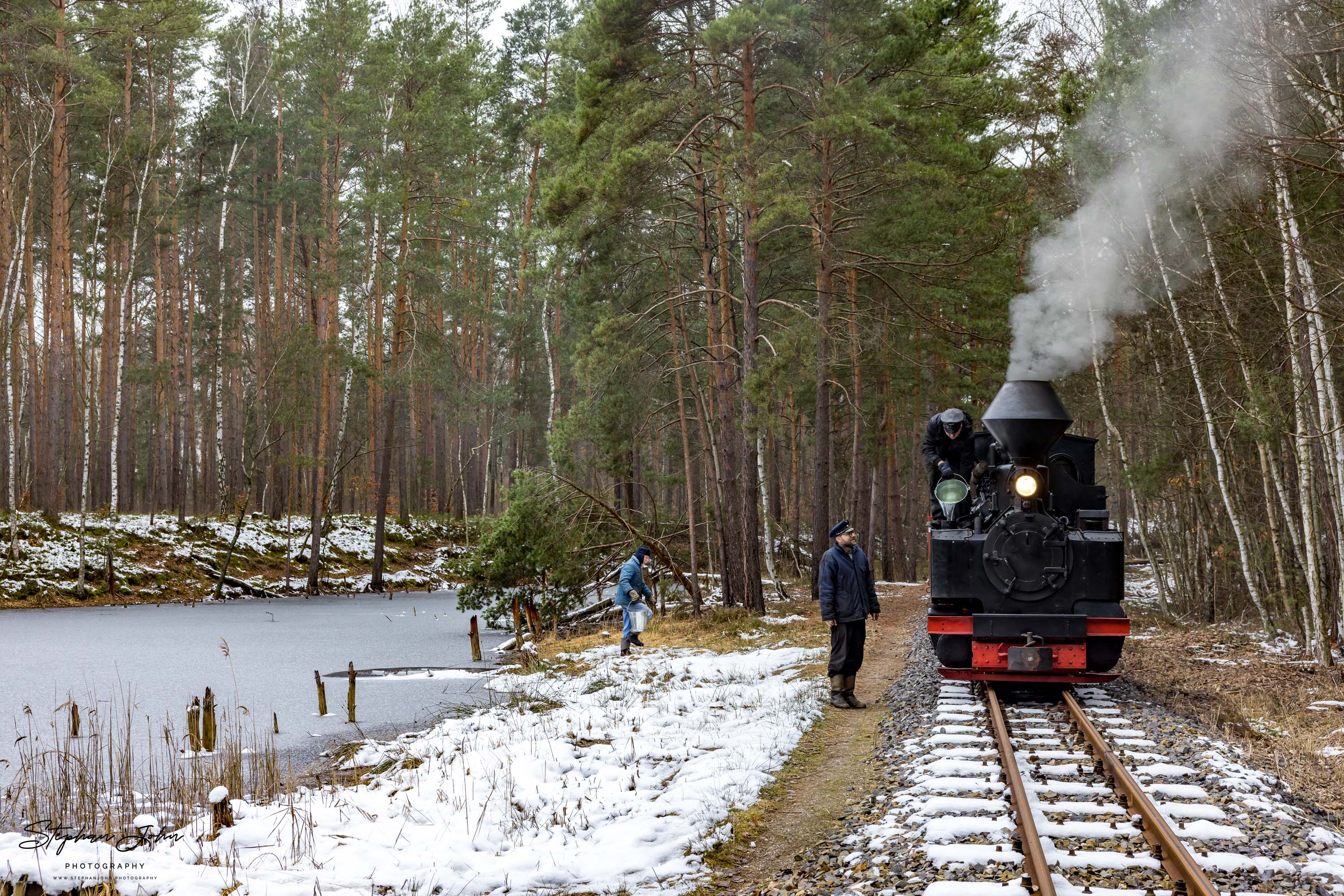 Lok 99 3315-1 mit einem Güterzug nach Weißwasser. An einem Waldteich werden mit Eimern die Wasservorräte der Lok ergänzt