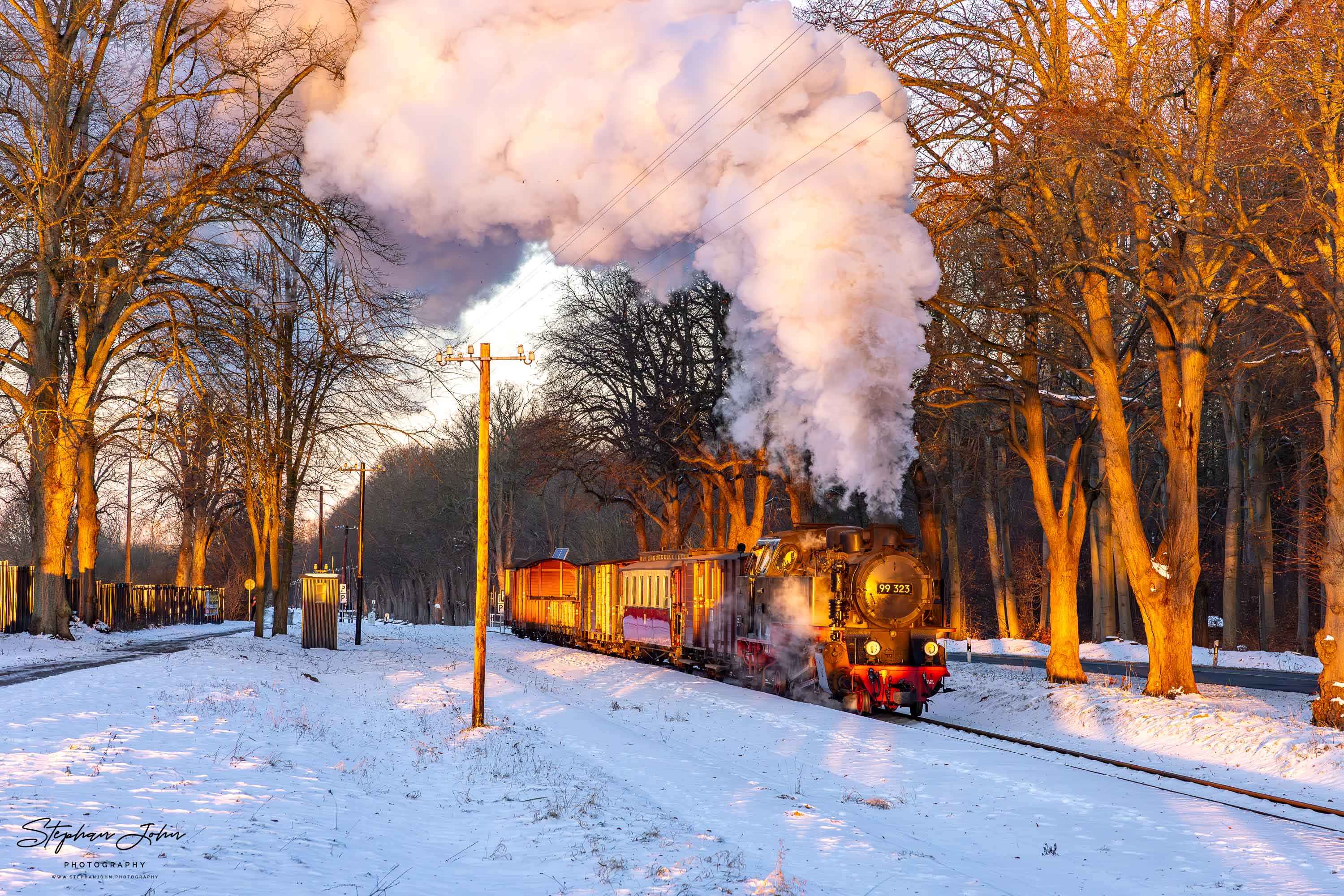 Lok 99 323 fährt im Morgenlicht mit einem GmP durch den Bahnhof Rennbahn