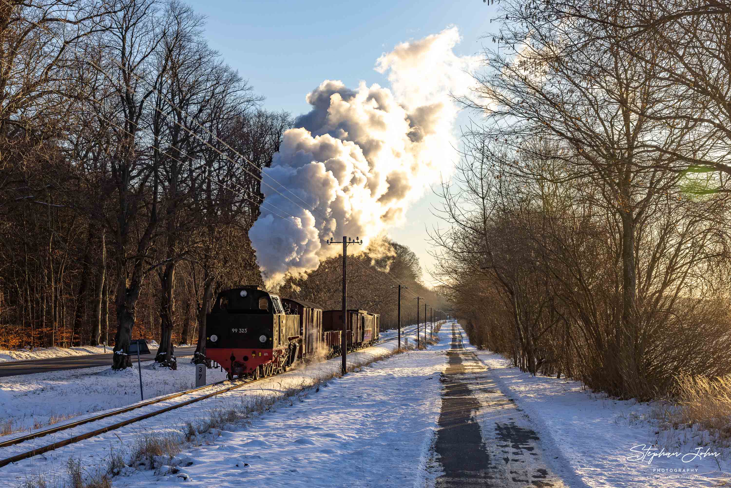 Lok 99 323 fährt im Morgenlicht mit einem GmP durch den Bahnhof Rennbahn